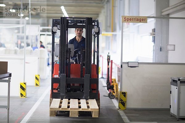 Erwachsener Mann mit Gabelstapler in der Fabrik