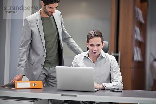 Zwei Männer im Büro  einer mit Laptop