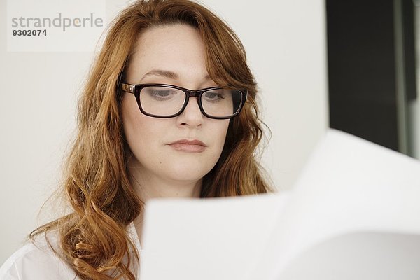 Nahaufnahme der mittleren erwachsenen Geschäftsfrau beim Lesen von Papierkram