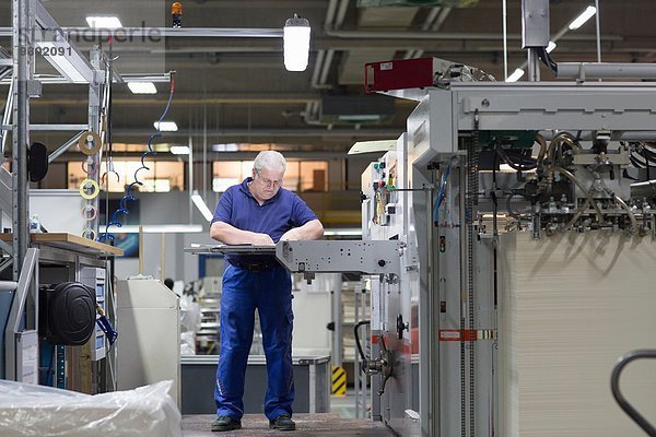Arbeiter mit Maschine in der Papierverpackungsfabrik