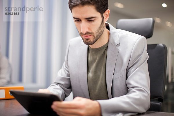 Junger Mann mit digitalem Tablett im Büro