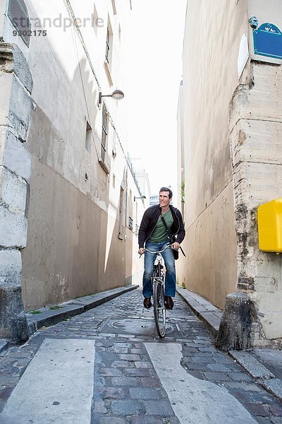 Mittlerer Erwachsener  der auf der schmalen Kopfsteinpflasterstraße radelt  Paris  Frankreich