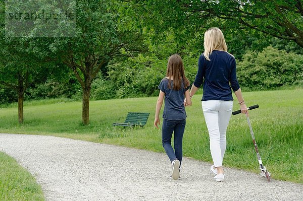 Mutter und Tochter beim Spaziergang im Park mit dem Roller