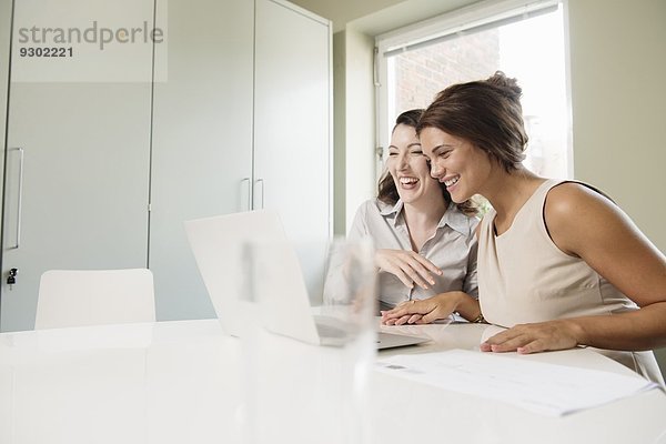 Zwei Geschäftsfrau lachend und auf den Laptop schauend
