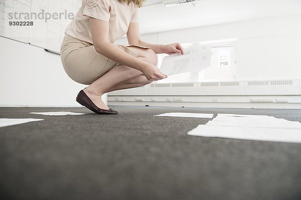 Junge Geschäftsfrau organisiert Papierkram auf leerer Büroetage