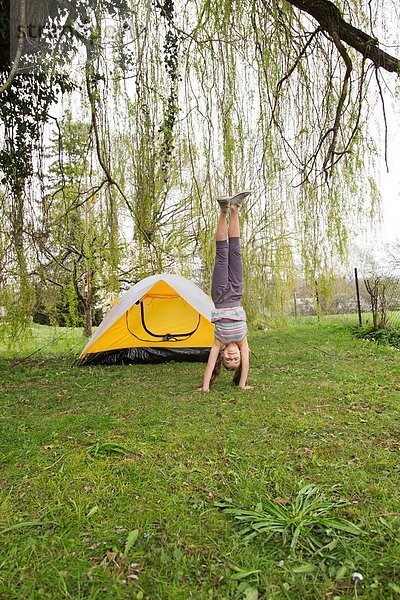 Lächelndes Mädchen beim Handstand im Garten