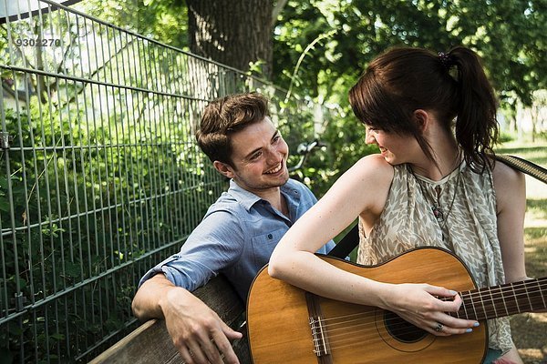 Junges Paar spielt Akustikgitarre im Park