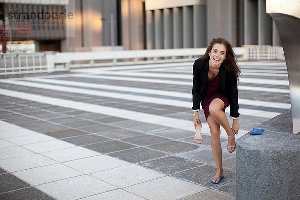 Junge Geschäftsfrau tauscht Sandalen gegen Flipflops aus