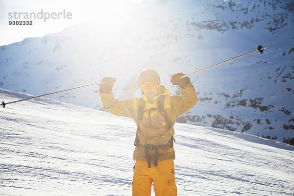 Mittlerer erwachsener Skifahrer  der Skistöcke hochhält  Österreich