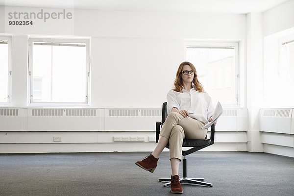 Mittlere erwachsene Geschäftsfrau auf Bürostuhl im neuen Büro