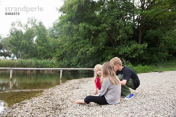 Bruder und zwei Schwestern beim Plaudern am Seeufer