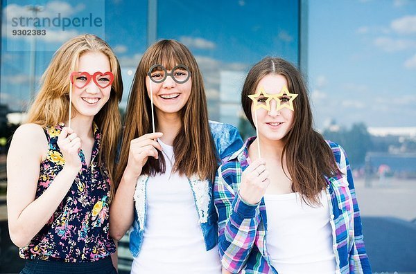 Porträt von drei jungen Frauen  die Brillenmasken hochhalten