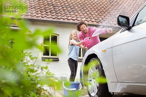 Mädchen hilft Vater beim Autowaschen