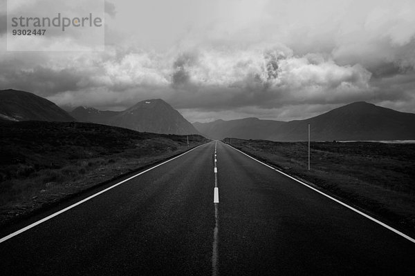 Schwarz-Weiß-Bild von gerader Straße und Bergen  Scottish Highlands  Schottland