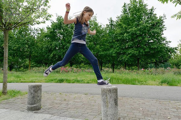 Mädchen springen Poller in der Luft im Park