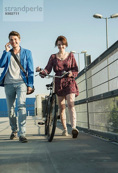 Junges Paar schiebt Fahrrad über Brücke