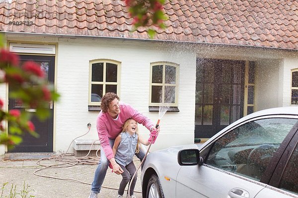 Mädchen hilft Vater beim Autowaschen