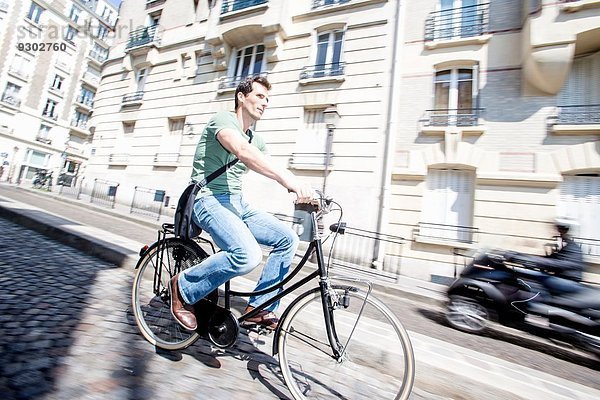 Mittlerer erwachsener Radfahrer  der die Kopfsteinpflasterstraße hinunterfährt  Paris  Frankreich