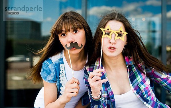 Porträt von zwei jungen Frauen mit Schnurrbart und Brille Kostümmasken