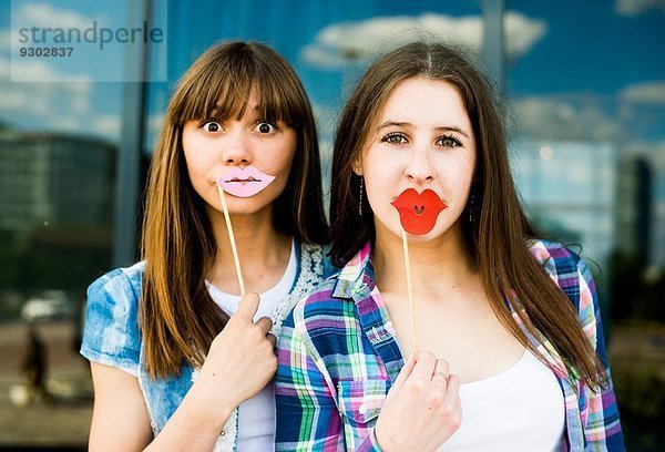 Porträt von zwei jungen Frauen  die Lippenmasken hochhalten