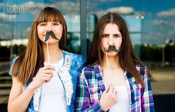 Porträt von zwei jungen Frauen mit Schnurrbart Kostümmasken