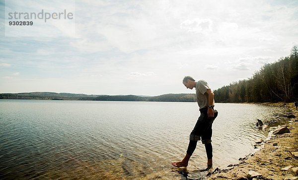 Junger männlicher Wanderer  der ängstlich im See paddelt.