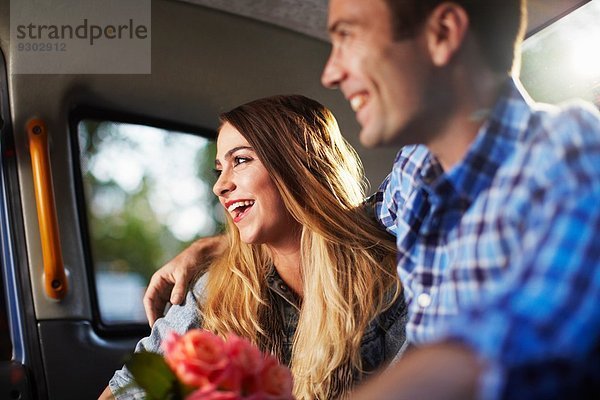 Junge Frau mit Freund und Rosenstrauß im Stadttaxi