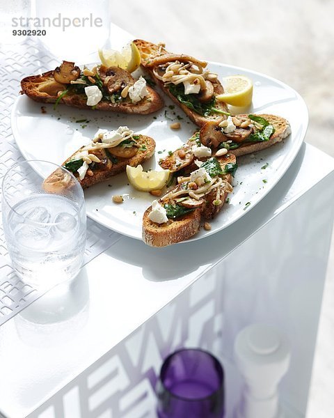 Teller mit Champignon und Spinatbruschetta mit Zitronenscheibe