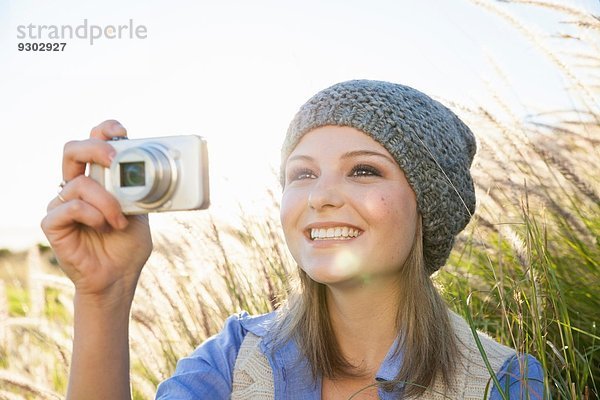 Junge Frau beim Fotografieren mit der Kamera auf dem Feld