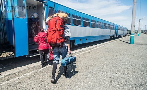Rückansicht junger Wanderer mit Rucksäcken im Zug