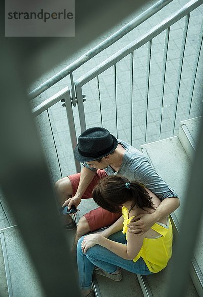 Hochwinkelansicht eines jungen Paares  das auf einer Treppe sitzt.