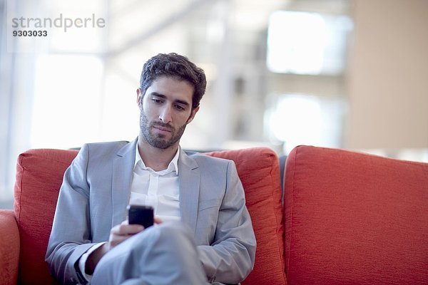 Jungunternehmer Smartphone SMS auf Sofa im Konferenzzentrum