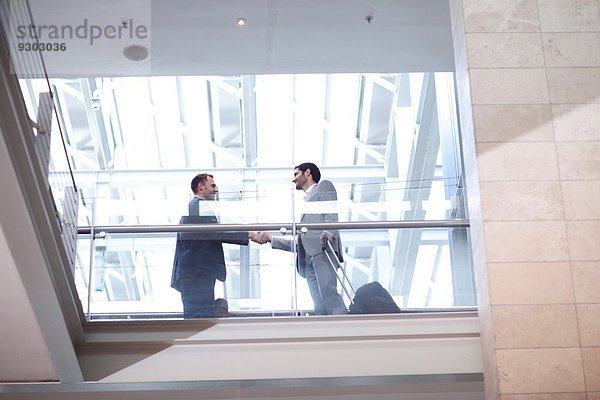 Zwei junge Geschäftsleute beim Händeschütteln auf dem Balkon des Konferenzzentrums