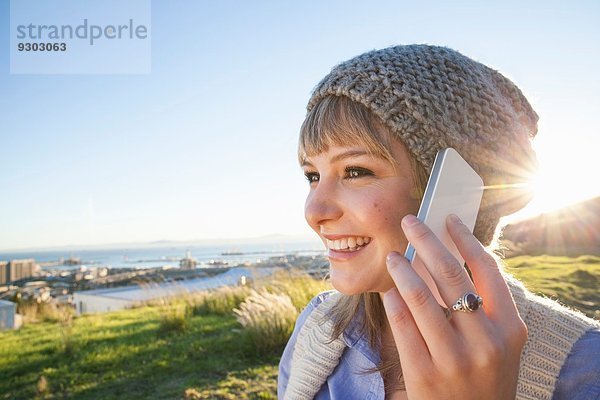 Junge Frau beim Chatten auf dem Smartphone  Blick auf den Hafen im Hintergrund  Kapstadt  Südafrika