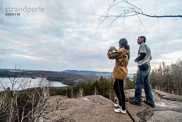 Junges Paar auf dem Gipfel einer Felsformation fotografiert die Aussicht