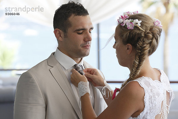 Braut rückt dem Bräutigam die Krawatte zurecht