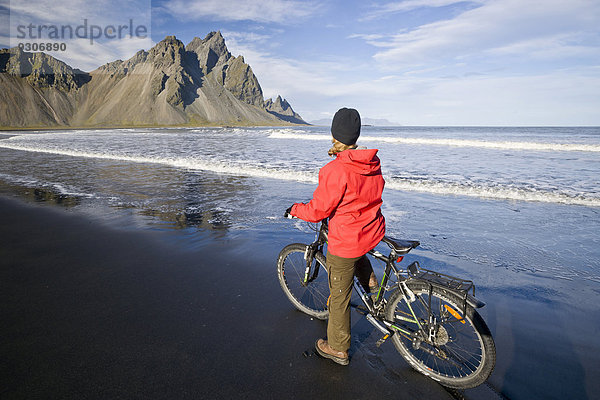 Frau fährt Fahrrad am Strand vor Berg Vestrahorn nahe Hoefn  Stokksnes  Südwesten  Island