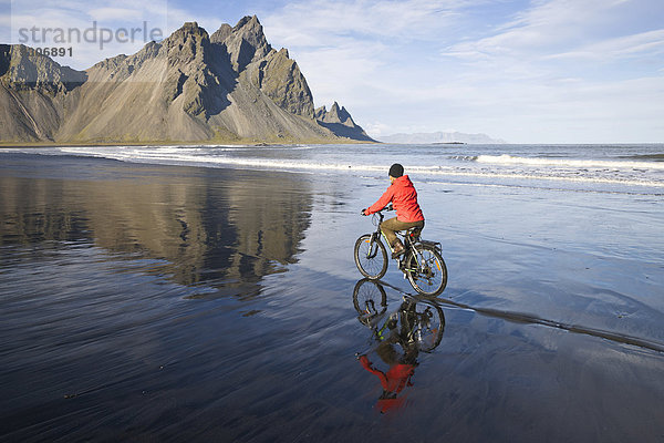 Frau fährt Fahrrad am Strand vor Berg Vestrahorn nahe Hoefn  Stokksnes  Südwesten  Island