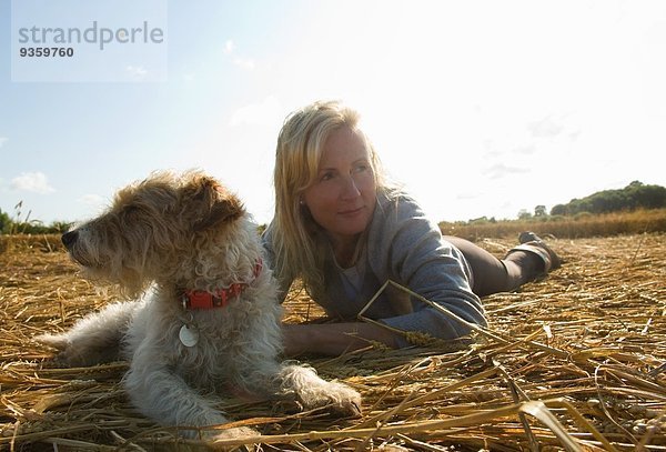 Frau und Jack Russell Terrier auf dem Feld liegend