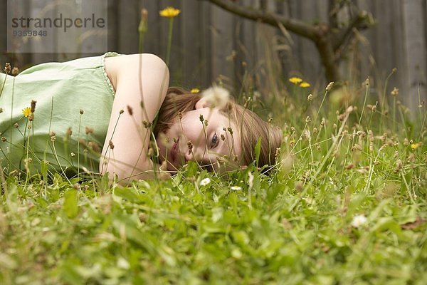 Mädchen auf Gartengras liegend tagträumend