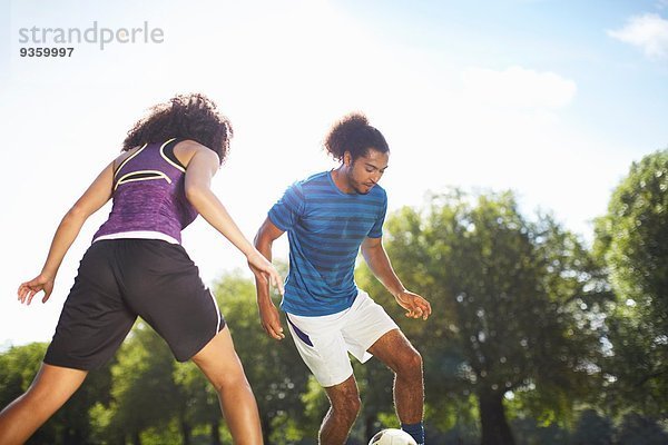 Junges Paar spielt Fußball im Park