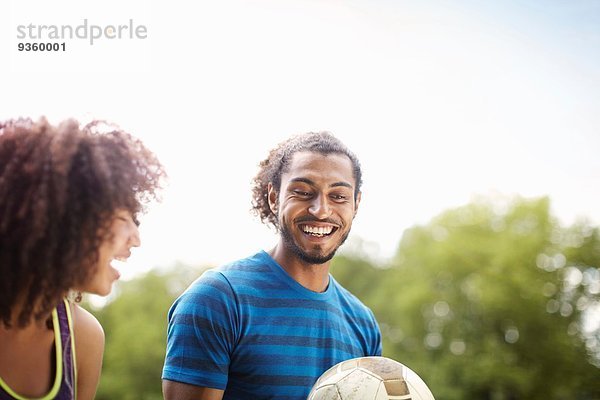 Junges Fußballpärchen beim gemeinsamen Plaudern und Lachen im Park