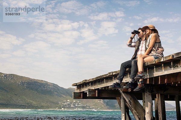 Junges Paar am Rande des alten Piers mit Blick durchs Fernglas  Kapstadt  Western Cape  Südafrika