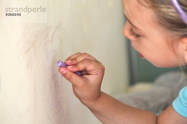 Junges Mädchen malt mit Kreide an der Wand