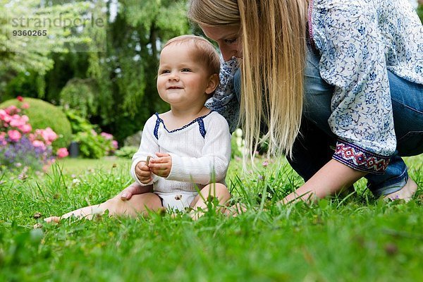 Mutter mit Mädchen auf Gras sitzend