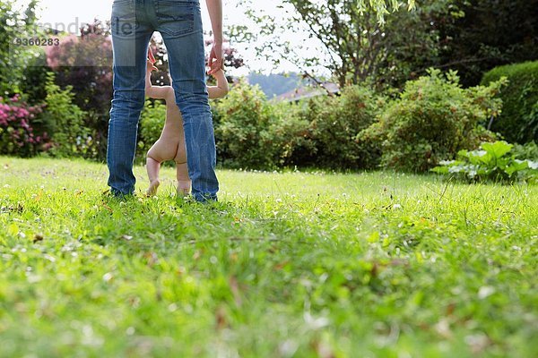 Rückansicht des erwachsenen Mannes und der schwankenden Tochter im Garten