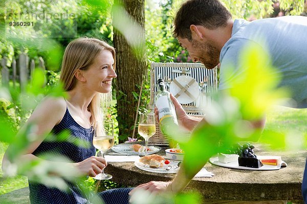 Mittleres erwachsenes Paar beim Picknick mit Weißwein im Garten