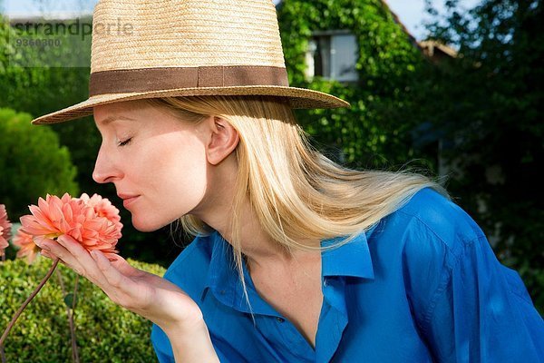 Nahaufnahme einer erwachsenen Frau  die Gartenblüte riecht.