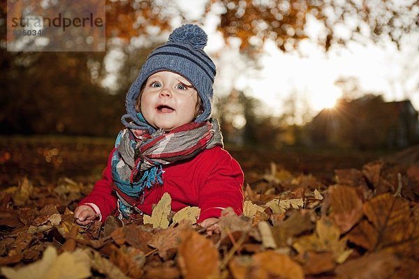 Junges Mädchen im Herbstlaub sitzend