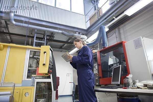 Ingenieurin bei der Überwachung von Fabrikmaschinen mit Hilfe eines digitalen Tabletts